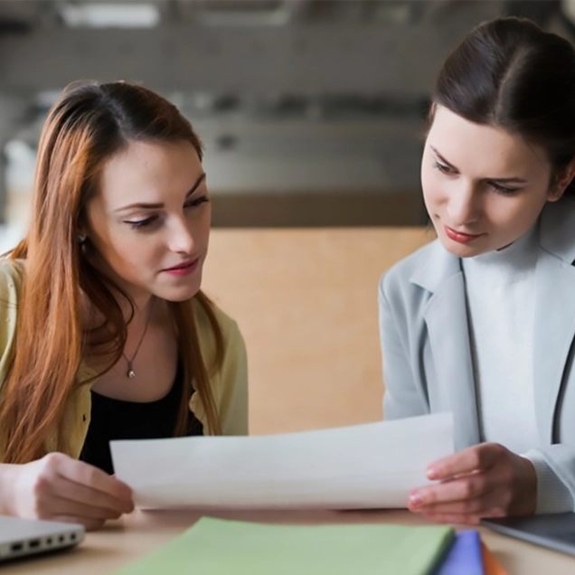 Two women discussing a document with australia immigration consultants in kerala.